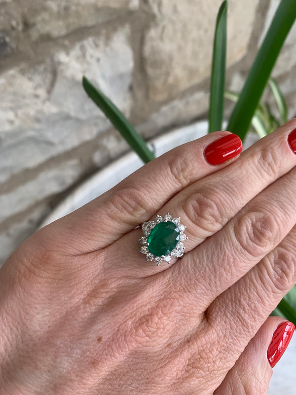 Oval shaped Emerald and Diamond cluster ring set in 18ct white gold